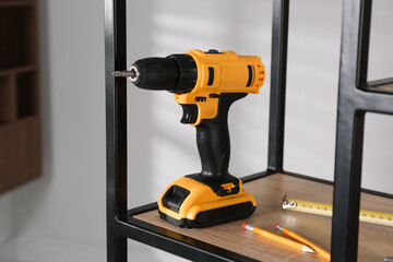 Electric screwdriver, pencils and tape measure on shelving unit indoors