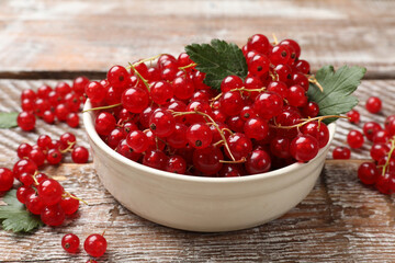 Fresh red currants in bowl on wooden table, closeup