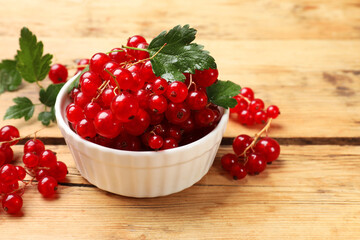 Fresh red currants and green leaves on wooden table, closeup