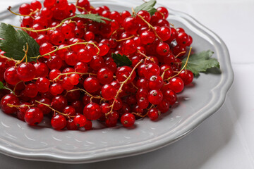 Fresh red currants and leaves on white table, closeup