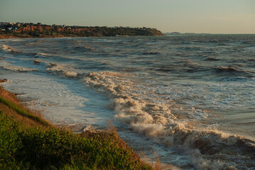 Sunset at sea during a storm. Coast with waves in sea on sunset. Waves in sea during storm and wind. Wave from the sea goes on land to the beach. Splashing Waves, Seaside.