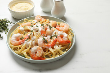 Delicious pasta with shrimps and creamy sauce on white table. Space for text