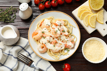 Tasty pasta with shrimps, creamy sauce and cheese on wooden table, flat lay