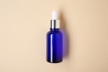 Essential oils in bottle on beige background, top view