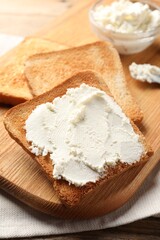 Delicious toasted bread slices with cream cheese on table