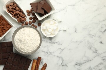 Flat lay composition with flour, chocolate and other ingredients for making dough on white marble table. Space for text