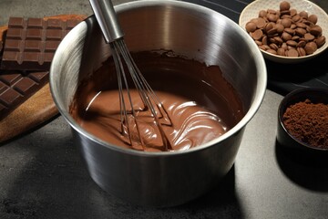Chocolate dough in bowl and ingredients on grey table