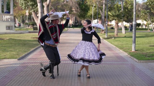 pareja de huasos bailando cueca chilena en la plaza de la ciudad