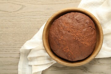 Chocolate dough in bowl on wooden table, top view
