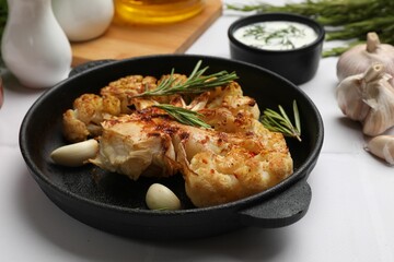 Delicious baked cauliflower steaks served on white tiled table, closeup