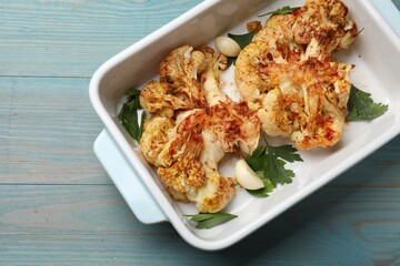 Delicious baked cauliflower steaks on blue wooden table, top view