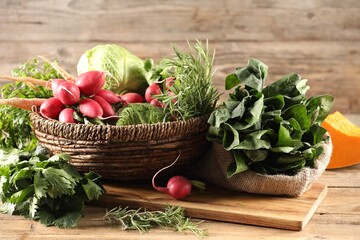 Different fresh herbs, cabbages, radishes and pumpkin on wooden table