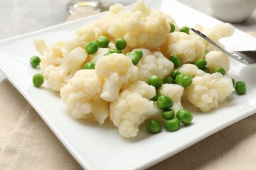 Tasty cooked cauliflower with green peas on table, closeup
