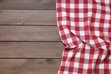 Obraz premium Crumpled tablecloth with checkered pattern on wooden table, top view. Space for text