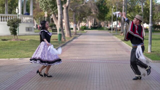 pareja de huasos bailando cueca chilena en la plaza de la ciudad