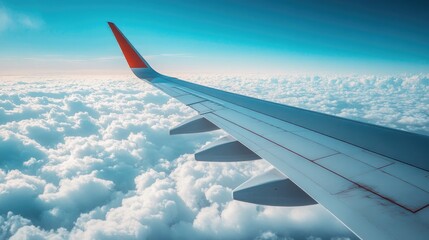 Obraz premium A view of a modern airplane wing against a clear blue sky, with fluffy white clouds below, symbolizing travel and adventure.