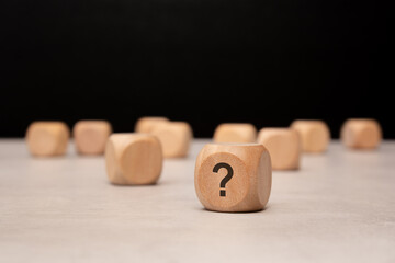 Wooden blocks featuring a prominent question mark arranged thoughtfully on a table surface