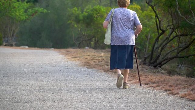 Slow motion, elderly woman walking outdoors in a healthy activity.