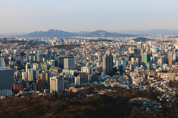 Beautiful vibrant aerial sunset view of Seoul, South Korea skyline, with mountains and sprin scenery beyond the city, seen from observation deck of Namsan Park, Gyeonggi-do province, Republic of Korea