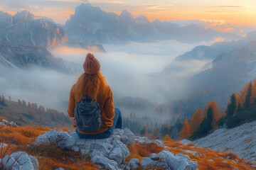 Fototapeta premium Sporty young woman hiking on mountain peak overlooking autumn valley at colorful sunset in dolomites