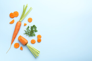 Whole and cut fresh carrots with green leaf on light background, flat lay. Space for text