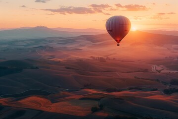 Fototapeta premium As the sun sets, a solitary hot air balloon floats serenely above golden fields, casting a gentle shadow on the vast landscape while colors blend in the evening sky
