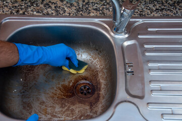 Close-up cleaning the dirty sink in the kitchen by scrubbing it with a sponge