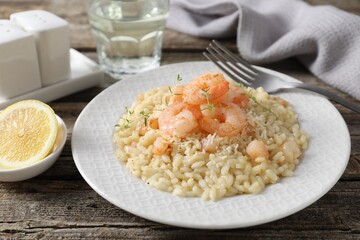 Delicious risotto with shrimps and cheese served on wooden table, closeup