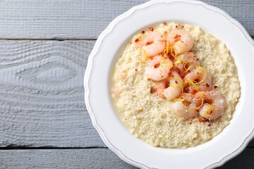 Delicious risotto with shrimps and cheese on grey wooden table, top view. Space for text