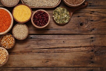 Different types of cereals, seeds and legumes on wooden table, flat lay. Space for text