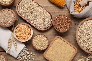 Different types of cereals and legumes on wooden table, flat lay