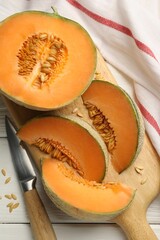 Cut ripe Cantaloupe melon and knife on white wooden table, flat lay