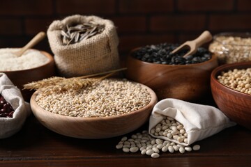 Different types of cereals, seeds and legumes on wooden table