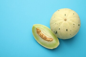 Fresh ripe honeydew melons on light blue background, top view. Space for text