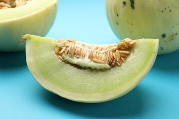 Cut fresh ripe honeydew melon on light blue background, closeup