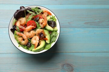 Delicious shrimp salad on light blue wooden table, top view. Space for text