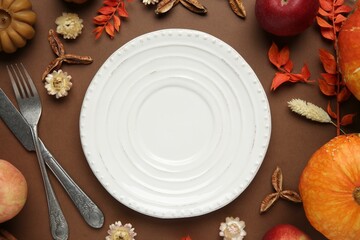 Beautiful table setting with autumn decor on brown background, flat lay