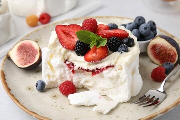 Pavlova cake (meringue dessert) with whipped cream, fresh berries, mint and fig on table, closeup