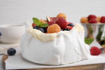 Pavlova cake (meringue dessert) with whipped cream, fresh berries and mint on table, closeup