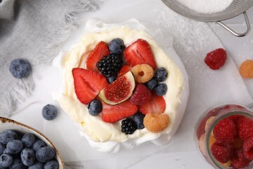 Pavlova cake (meringue dessert) with whipped cream, fresh berries and fig on table, flat lay