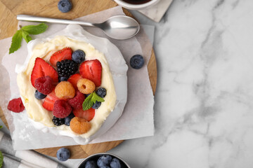 Pavlova cake (meringue dessert) with whipped cream, fresh berries and mint on white marble table, flat lay. Space for text