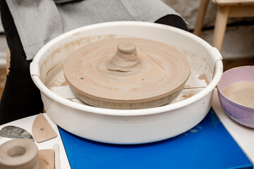 Clay in the center of pottery wheel to start forming the right size and shape of the project. Learning how to use a pottery wheel in ceramics class.