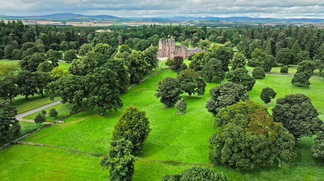 Drone view of Glamis Castle with towers and beautiful garden in Scotland. Aerial view of Scottish landmark with thick walls, and a modern parapet.