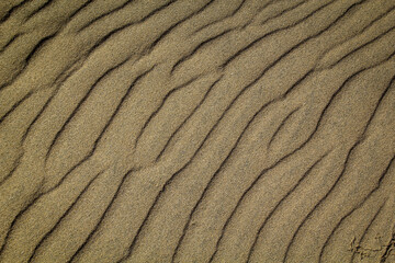 Eine durch Wind und Wellen entstandene Sandtextur am Strand.
