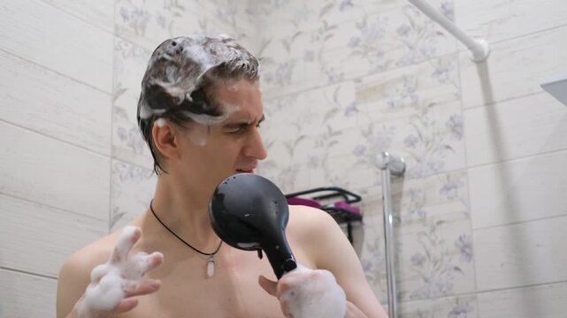Cheerful young guy singing in the shower while bathing