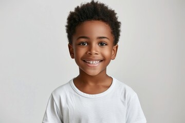 Happy African American schoolboy in white t shirt smiling at camera.