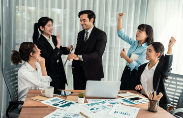 Group of happy businesspeople in celebratory gesture and successful efficient teamwork. Diverse race office worker celebrate after made progress on marketing planning in corporate office. Habiliment
