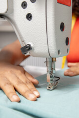 Woman hands sewing fabric on sewing machine highlighting the needle and thread
