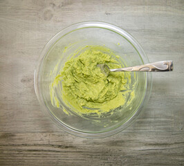 One avocado mashed in a glass bowl. Step for making dark chocolate avocado truffles.