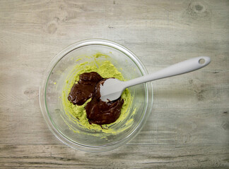 Fototapeta premium Mashed avocado and melted dark chocolate in a glass bowl to make dark chocolate avocado truffles. Keto an vegan dessert.